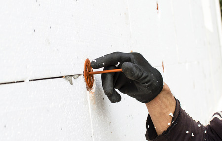 The process of fixing dowel-umbrella on the walls with foam plasticの写真素材