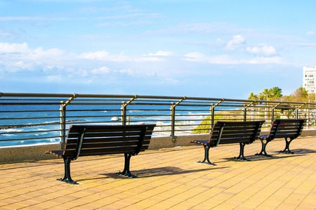 Three Wooden benches in the park on a background of blue sky and seaの写真素材