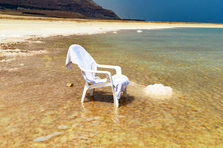 White chair in the water of the Dead Sea on a background of blue skyの写真素材