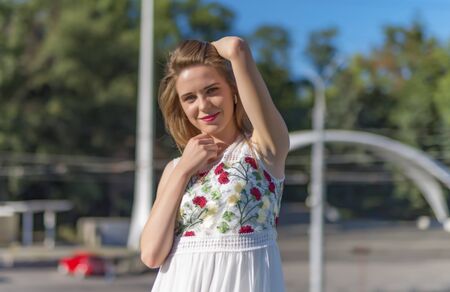 Beautiful girl enjoys sunlight on the background of the city streetの写真素材