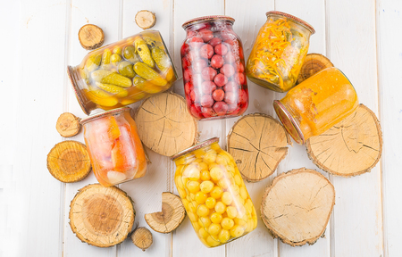 Different preserves in glass jars against the background of a tree tableの写真素材