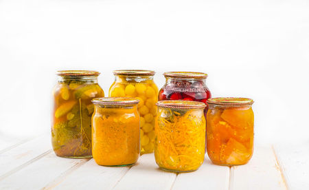 Different preserves in glass jars against the background of a tree tableの写真素材