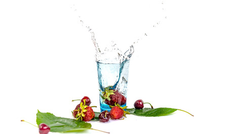 Strawberries fall in a glass of water on a white backgroundの写真素材