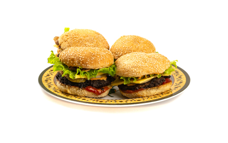 Four Hamburgers with cheese and salad on a plate on a white backgroundの写真素材