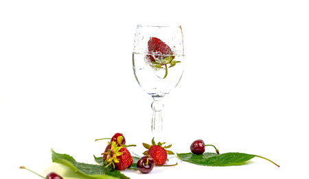 Strawberries fall in a glass of water on a white backgroundの写真素材