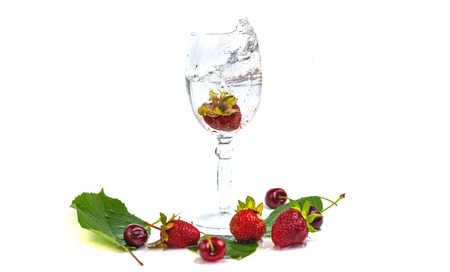Strawberries fall in a glass of water on a white backgroundの写真素材