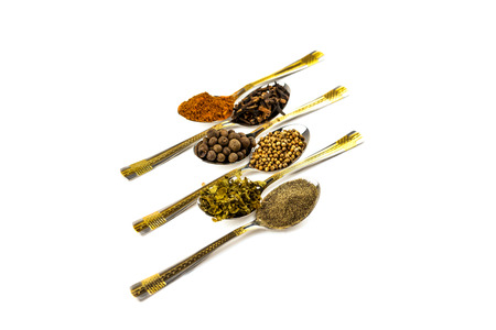 Spices in spoons - pepper, black, red, fragrant, cilantro coriander, and dried herbs on a white backgroundの写真素材