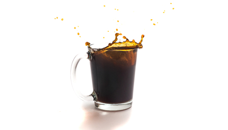 A cup of coffee with splashes in the process of spilling on a white backgroundの写真素材