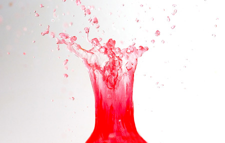 Beautiful splashes of red liquid on a light backgroundの写真素材