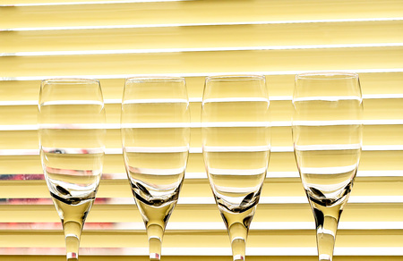 Glass glasses for champagne on the background of curtain blindsの写真素材