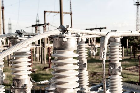 High voltage porcelain insulators with aluminum cable on blurred power plant backgroundの写真素材