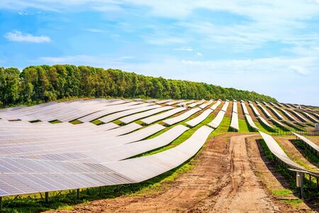 Rows of sections of solar panels on steep hills fields on sky background