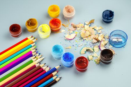 Sharpened multicolored sharpened pencils and jars with acrylic paint on a gray background