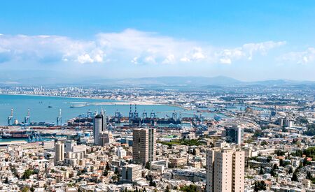 City with a seaport, lots of houses on a background of sea and mountains in the cloudsの写真素材