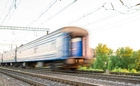 Train with blue passenger cars that are blurred at high speed