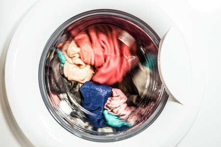 The process of unloading washed colorful clothes from the washing machine in the bathroomの写真素材