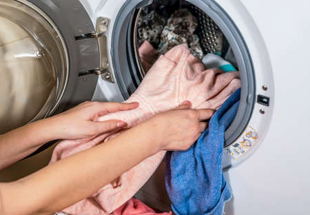 The process of unloading washed colorful clothes from the washing machine in the bathroomの写真素材