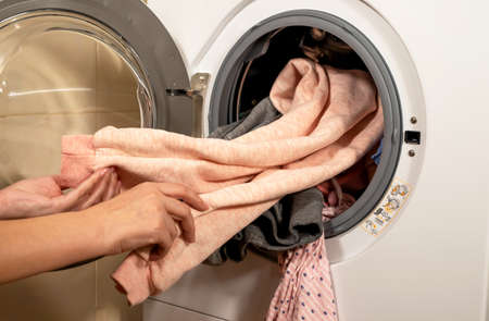 The process of unloading washed colorful clothes from the washing machine in the bathroomの写真素材