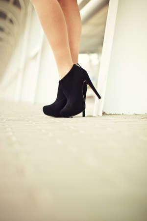 Beautiful female legs in black suede shoes with pavement in the backgroundの写真素材