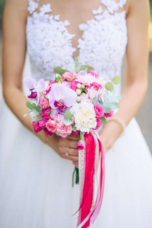 Gentle wedding bouquet of white and pink lowers in the hands of the brideの写真素材