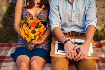 Man with sketchbook and woman with a bouquet sitting on a plaidの写真素材