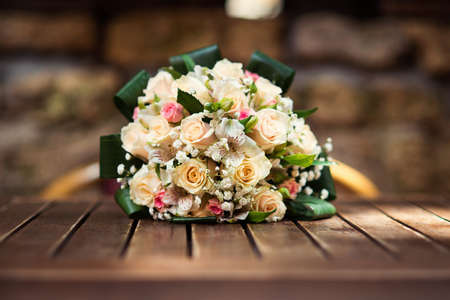 Stylish, beautifully decorated wedding bouquet of yellow and rose roses on wooden table.の写真素材