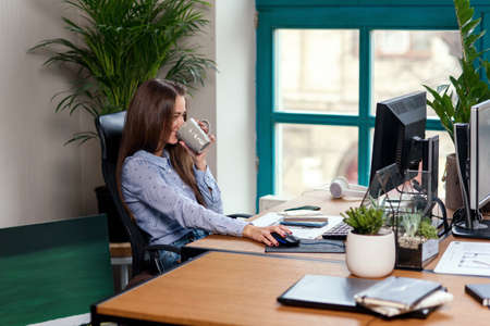 Office worker taking a coffee break with a cup of espresso in her hands.の写真素材