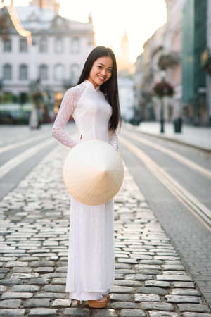 Beautiful young asian girl in national traditional Ao Dai white dress with vietnamese conical hat...