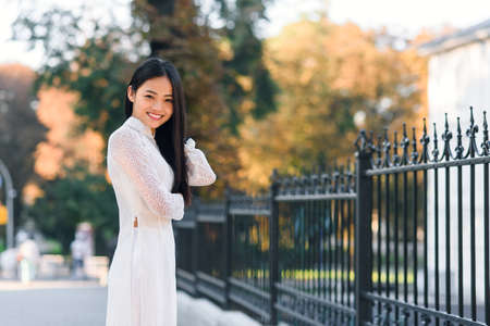 Beautiful vietnamese girl dressed traditional Ao Dai white dress. Ray of light on the background.の写真素材