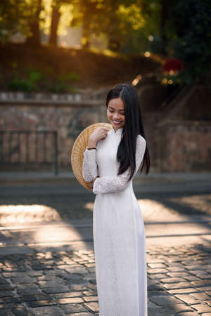 Beautiful vietnamese girl dressed traditional Ao Dai white dress. Ray of light on the background.の写真素材
