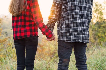 Close up young man and his girlfriend in casual clothes holds the hands to each other. Happy couple with guitar having rest on picnic in the park.の写真素材