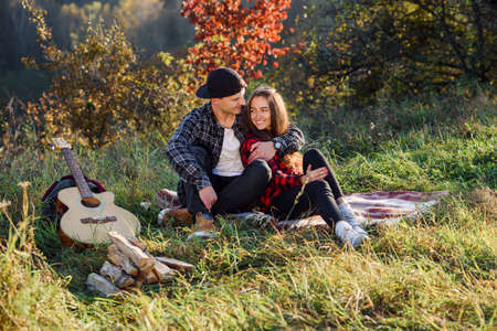 Happy young man hugs his girlfriend tenderness and having rest on picnic in the park. Couple in love having rest at sunset.の写真素材