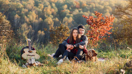 Happy caucasian couple with their dog sitting on the lawn in spring park. Young man and his girlfriend enjoying at the nature.の写真素材