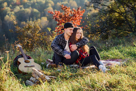 Happy young man hugs his girlfriend tenderness and having rest on picnic in the park. Couple in love having rest at sunset.の写真素材