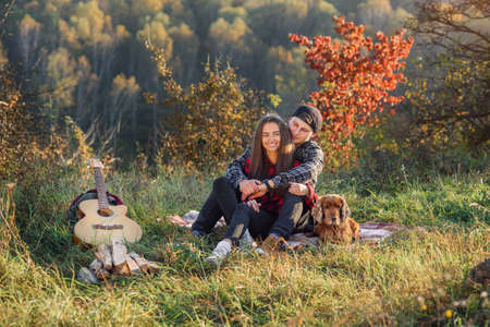 Happy caucasian couple with their dog sitting on the lawn in spring park. Young man and his girlfriend enjoying at the nature.の写真素材