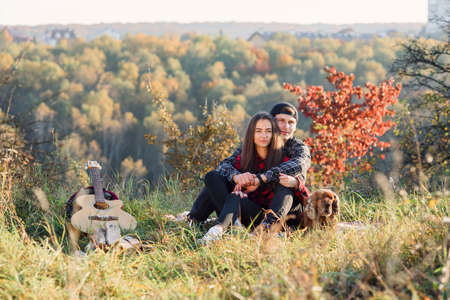 Happy caucasian couple with their dog sitting on the lawn in spring park. Young man and his girlfriend enjoying at the nature.の写真素材