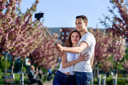 Passion and love concept. Man and woman kissing in blooming garden on spring day. Couple hugs near sakura trees. Couple in love spend time in spring garden.の写真素材