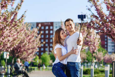 Passion and love concept. Man and woman kissing in blooming garden on spring day. Couple hugs near sakura trees. Couple in love spend time in spring garden.の写真素材