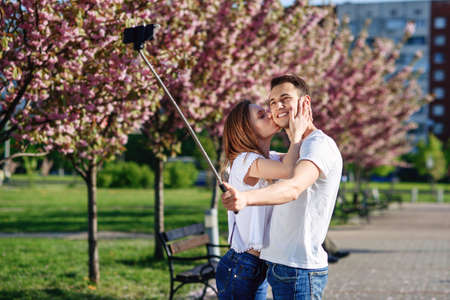 Passion and love concept. Man and woman kissing in blooming garden on spring day. Couple hugs near sakura trees. Couple in love spend time in spring garden.の写真素材