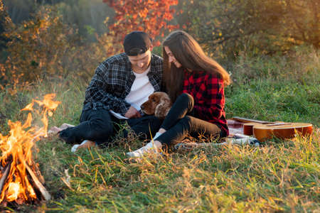 Happy caucasian couple with their dog sitting on the lawn in spring park. Young man and his girlfriend enjoying at the nature.の写真素材