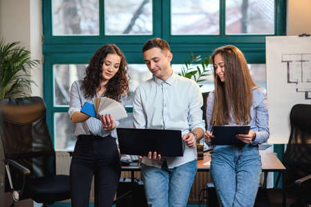 Young caucasian architects or designers using color palette for new project on the laptop in the stylish modern office with big window on background.の写真素材