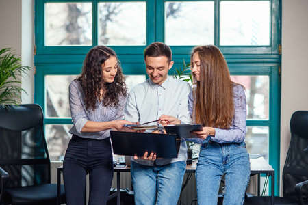 Young caucasian architects or designers using color palette for new project on the laptop in the stylish modern office with big window on background.の写真素材