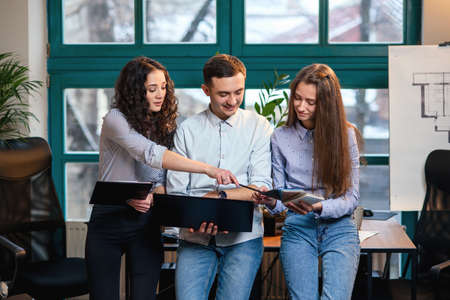 Young caucasian architects or designers using color palette for new project on the laptop in the stylish modern office with big window on background.の写真素材