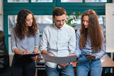 Young caucasian architects or designers using color palette for new project on the laptop in the stylish modern office with big window on background.の写真素材
