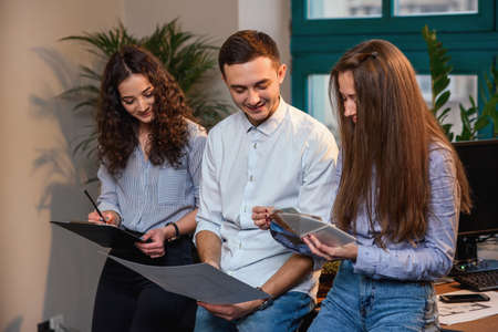 Young caucasian architects or designers using color palette for new project on the laptop in the stylish modern office with big window on background.の写真素材