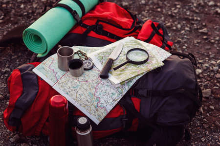 Close up shot of travel equipment, backpack, map, compass, knife, sleeping pad on the ground in...