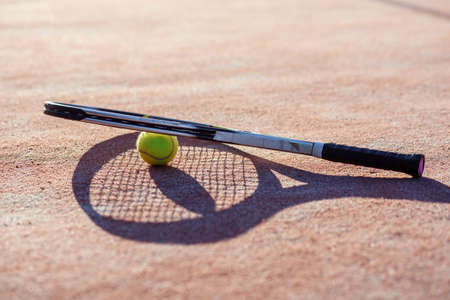 tennis rocket next to tennis ball on hard courtの写真素材