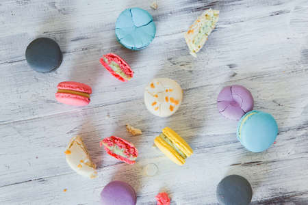 Multicolored french macaron cakes on the white wooden background. White, yellow, pink, purple and grey french macarons with fresh berries.の写真素材