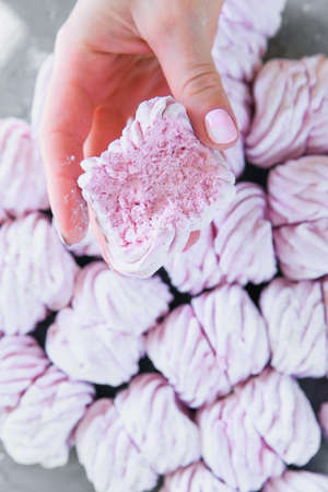Womans hands holds freshly prepared homemade marshmallow against a background of a lot ofmarshmallows. Natural marshmallowsの写真素材