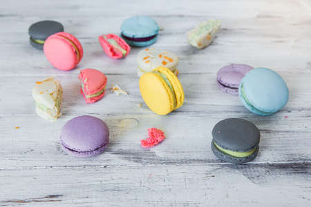 Colorful macaron cakes on the white wooden background. White, yellow, pink, purple and grey french macarons with fresh berries.の写真素材